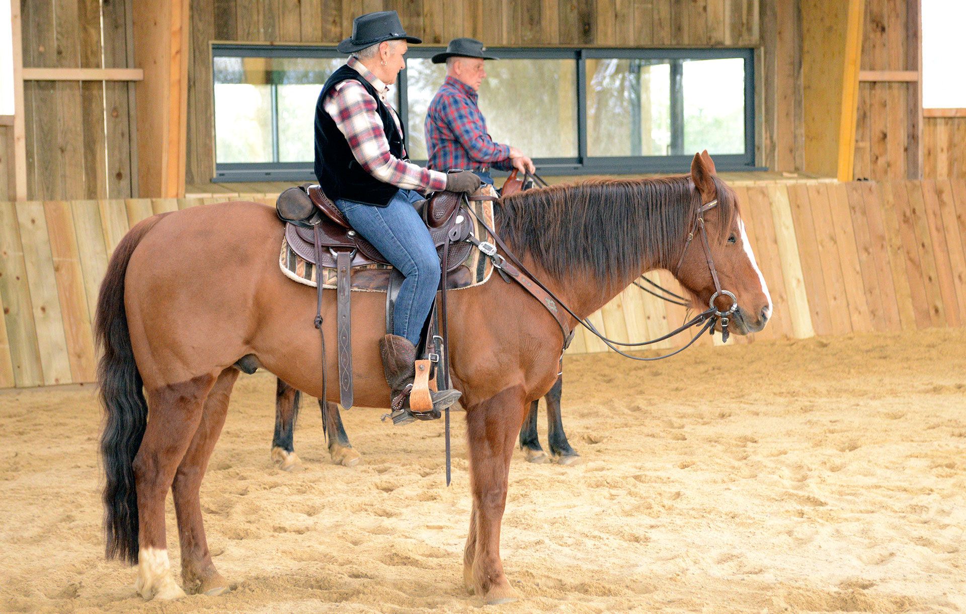 Dans un manège, deux cavaliers en selle pratiquent l’équitation western en loire-atlantique.  